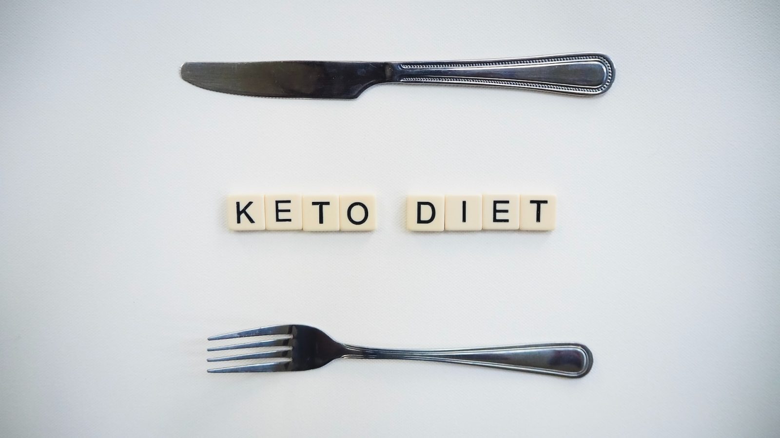 Der Schriftzug "Keto Diet" auf weißem Hintergrund, umrahmt von Gabel und Messer