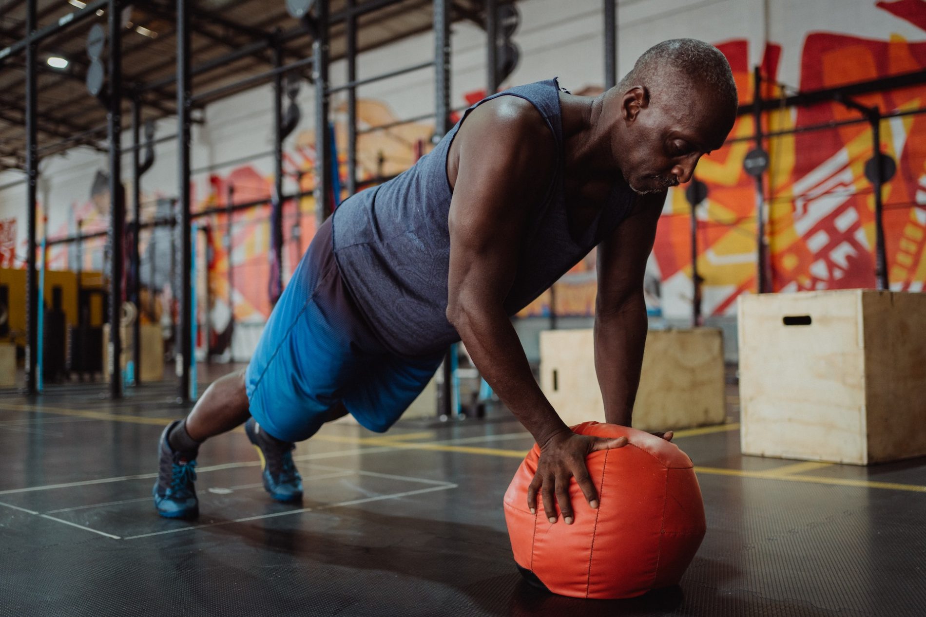 Ein Mann macht eine Unterarmstütze mit einem Gymnastikball in einem Fitnessstudio